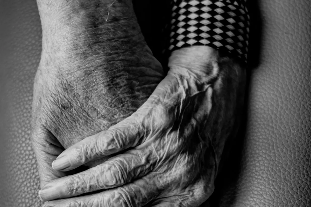 Fotografía en blanco y negro de las manos de una persona mayor, entrelazadas