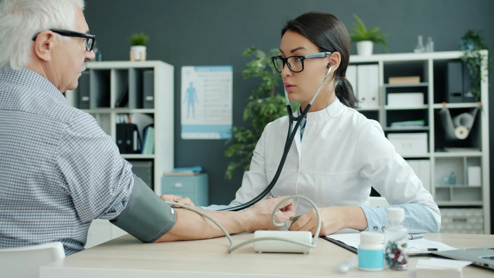 Médica tomando la presión arterial a un paciente mayor con un estetoscopio