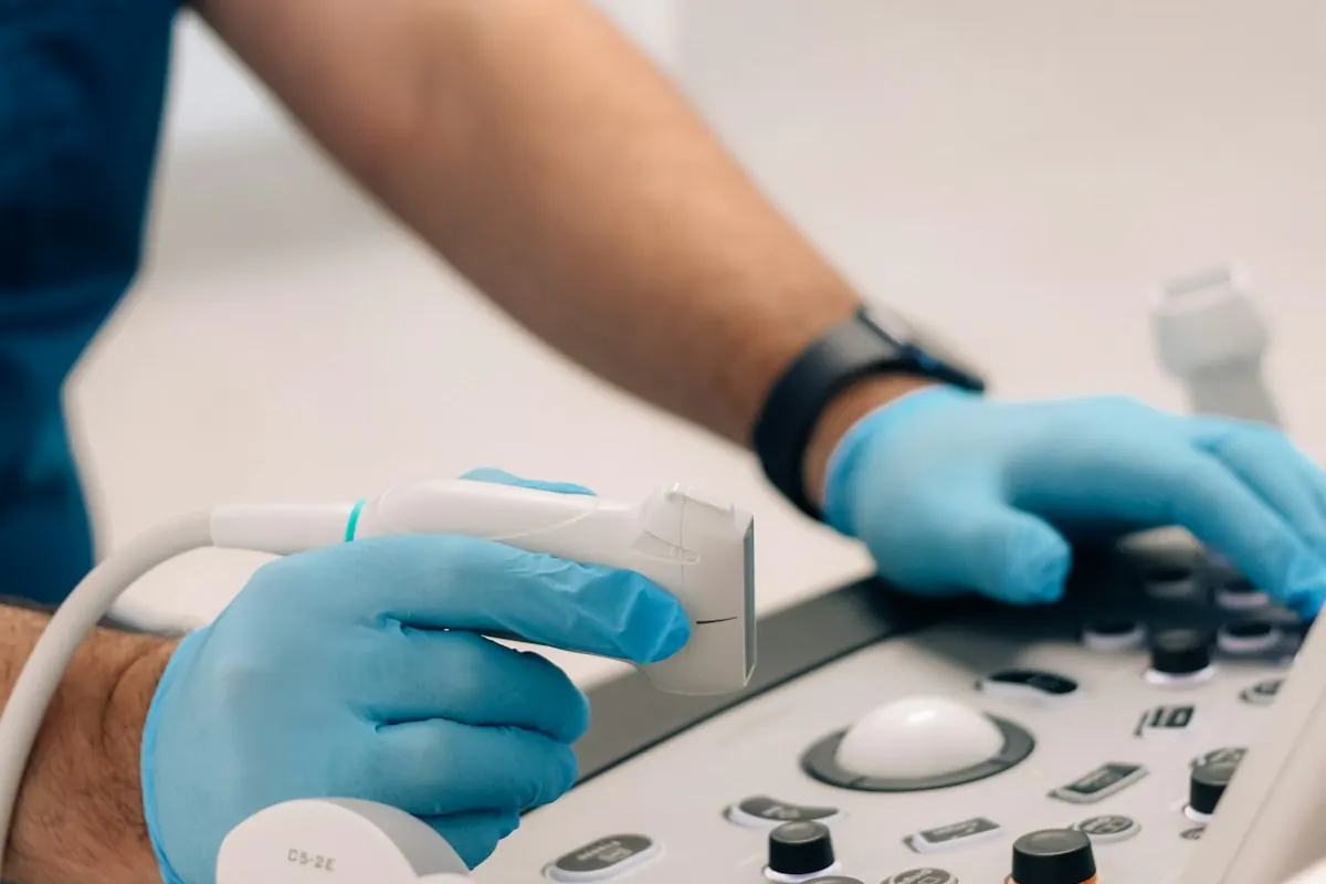 Profesional con guantes usando el transductor y la consola de un ecógrafo